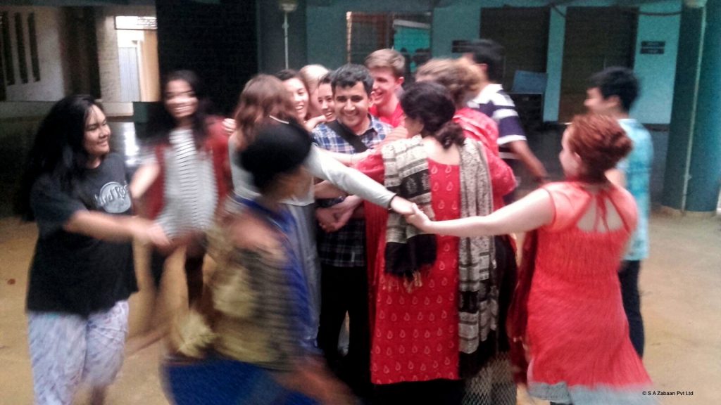 Ali smiling as Zabaan students circle around him during a group activity